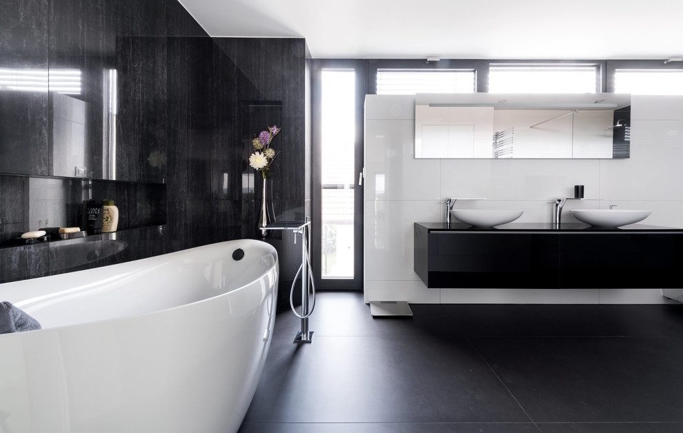 Foto på ett litet funkis svart en-suite badrum, med släta luckor, svarta skåp, ett fristående badkar, klinkergolv i keramik, ett fristående handfat och grått golv