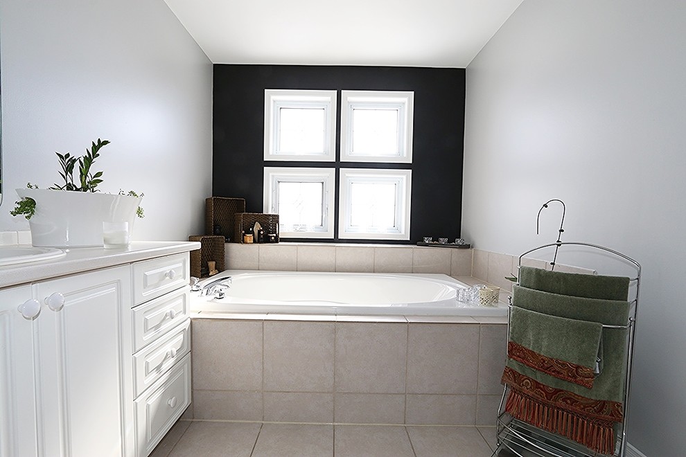 This is an example of a medium sized modern ensuite bathroom in Ottawa with beige tiles, black walls, raised-panel cabinets, white cabinets, a built-in bath, ceramic tiles, ceramic flooring and a built-in sink.