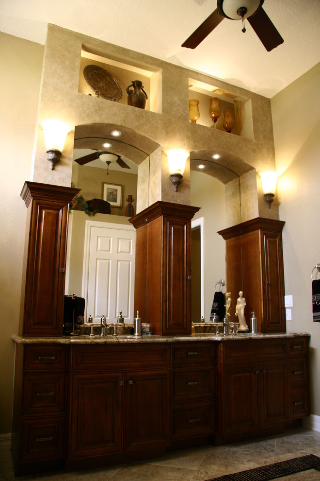 Aménagement d'une salle de bain principale classique en bois foncé de taille moyenne avec un placard avec porte à panneau surélevé, un mur beige, un sol en travertin, un lavabo encastré, un plan de toilette en granite et un sol marron.