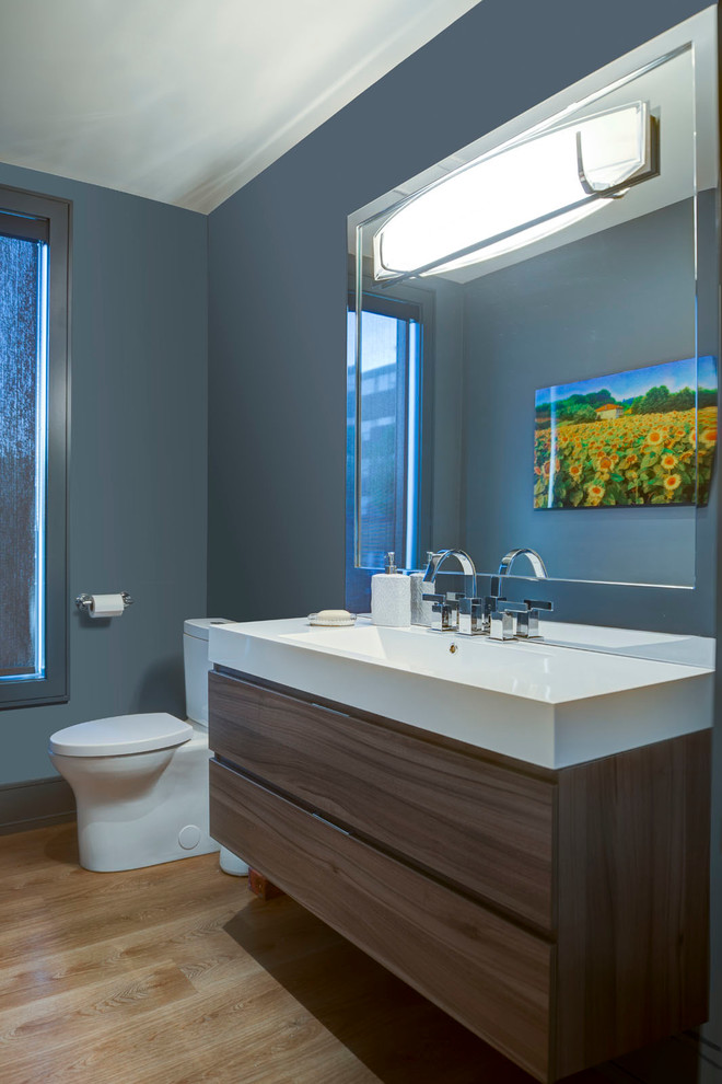 Ispirazione per una stanza da bagno con doccia minimalista di medie dimensioni con ante lisce, ante in legno scuro, WC a due pezzi, pareti blu, parquet chiaro, lavabo integrato, top in quarzo composito e pavimento marrone