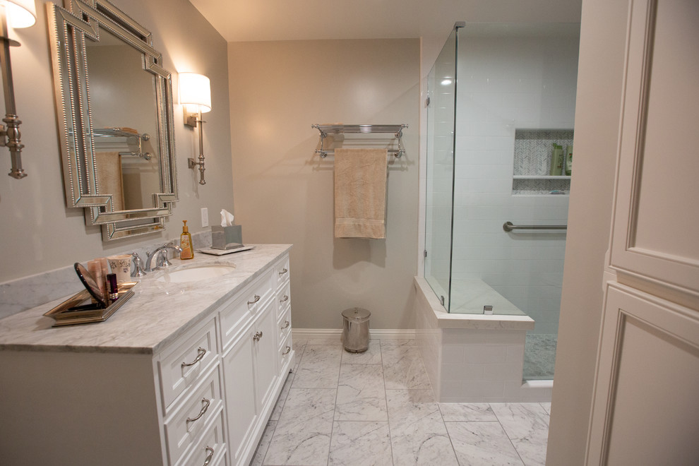 Exempel på ett mellanstort klassiskt vit vitt badrum med dusch, med vita skåp, en hörndusch, vit kakel, klinkergolv i porslin, ett undermonterad handfat, marmorbänkskiva, vitt golv, dusch med gångjärnsdörr, luckor med infälld panel och grå väggar