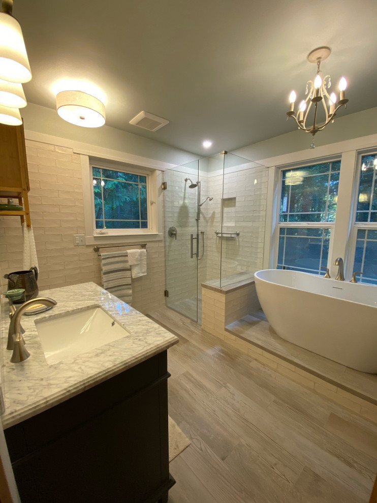 На фото: главная ванная комната в современном стиле с фасадами в стиле шейкер, синими фасадами, отдельно стоящей ванной, угловым душем, раздельным унитазом, бежевой плиткой, керамической плиткой, бежевыми стенами, полом из керамогранита, врезной раковиной, столешницей из искусственного кварца, бежевым полом, душем с распашными дверями, белой столешницей, нишей, тумбой под одну раковину, напольной тумбой и панелями на стенах с