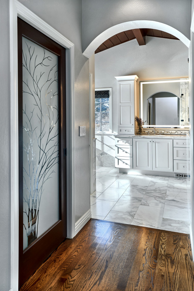 Example of a large transitional master gray tile and marble tile marble floor and gray floor bathroom design in San Francisco with raised-panel cabinets, white cabinets, a two-piece toilet, gray walls, an undermount sink, marble countertops, a hinged shower door and gray countertops