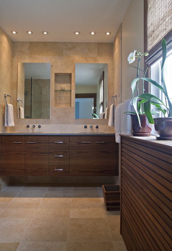 Example of a large trendy master stone tile and beige tile travertine floor alcove shower design in DC Metro with flat-panel cabinets, medium tone wood cabinets, beige walls, an undermount sink, solid surface countertops and a one-piece toilet