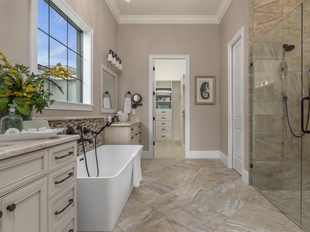 Design ideas for a traditional ensuite bathroom in Orlando with raised-panel cabinets, white cabinets, a freestanding bath, a walk-in shower, grey tiles, porcelain tiles, grey walls, a submerged sink and marble worktops.