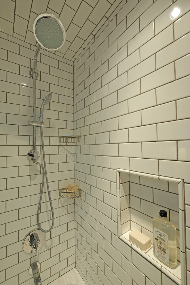 Inredning av ett klassiskt litet badrum, med skåp i mellenmörkt trä, vit kakel, vita väggar, ett undermonterad handfat, skåp i shakerstil, marmorbänkskiva, ett badkar i en alkov, en toalettstol med hel cisternkåpa, tunnelbanekakel, klinkergolv i keramik och en dusch/badkar-kombination