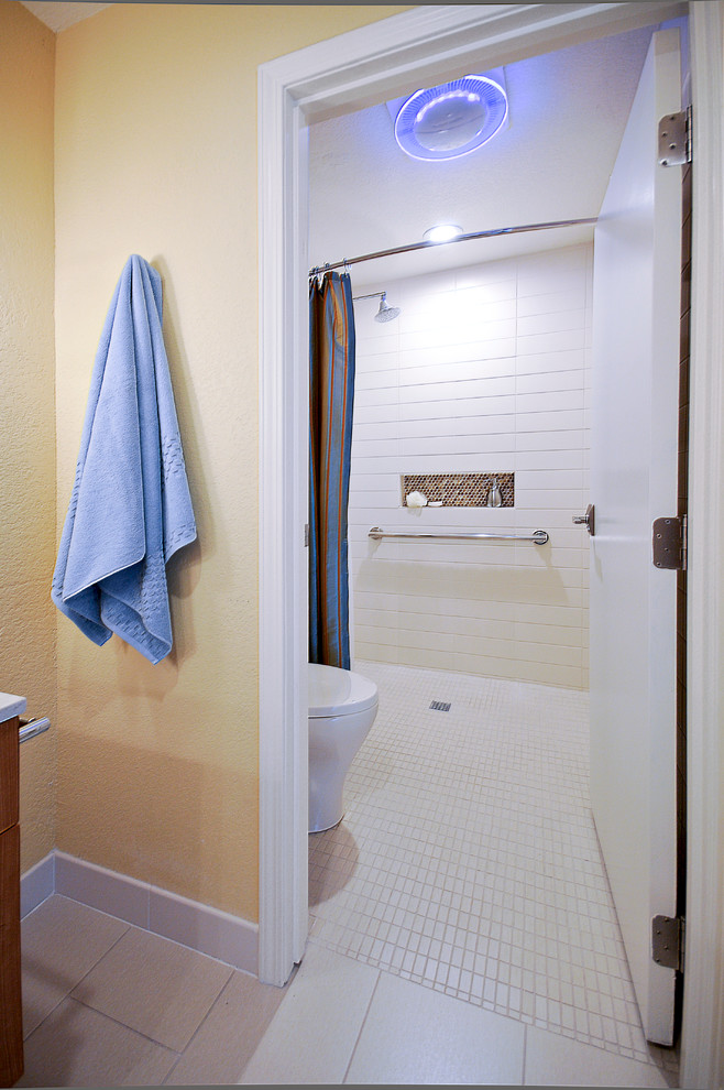Idéer för att renovera ett mellanstort funkis en-suite badrum, med släta luckor, skåp i mellenmörkt trä, en kantlös dusch, en toalettstol med hel cisternkåpa, vit kakel, gula väggar, klinkergolv i porslin, ett badkar i en alkov, tunnelbanekakel, ett undermonterad handfat och bänkskiva i kvarts