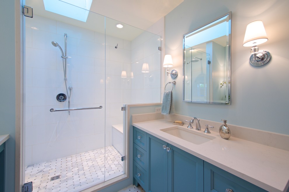 バンクーバーにある高級な広いトランジショナルスタイルのおしゃれなマスターバスルーム (アンダーカウンター洗面器、シェーカースタイル扉のキャビネット、青いキャビネット、珪岩の洗面台、ドロップイン型浴槽、オープン型シャワー、一体型トイレ	、モノトーンのタイル、青い壁、セラミックタイルの床) の写真
