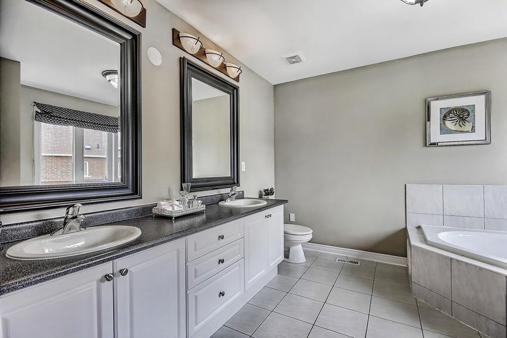 Inredning av ett klassiskt mellanstort en-suite badrum, med ett nedsänkt handfat, luckor med upphöjd panel, vita skåp, ett platsbyggt badkar, en dusch i en alkov, en toalettstol med hel cisternkåpa, grå kakel och beige väggar