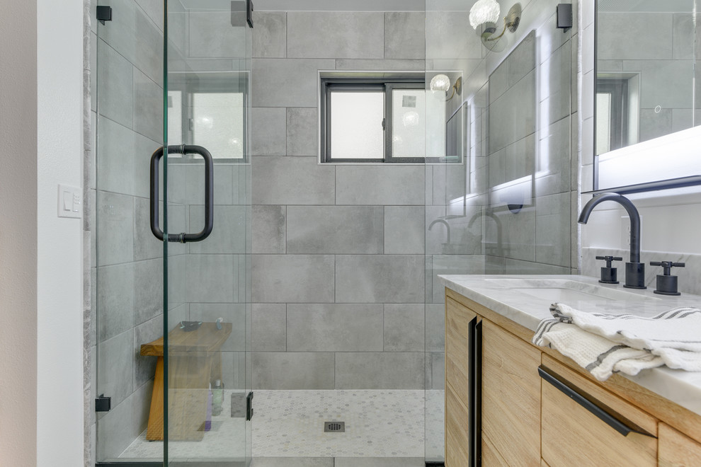 Idéer för ett mellanstort klassiskt grå en-suite badrum, med släta luckor, skåp i ljust trä, en dusch i en alkov, en toalettstol med hel cisternkåpa, grå kakel, porslinskakel, vita väggar, klinkergolv i porslin, ett undermonterad handfat, marmorbänkskiva, flerfärgat golv och dusch med gångjärnsdörr