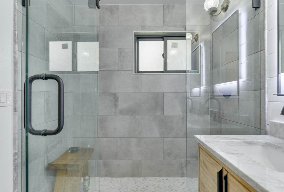 Bild på ett mellanstort vintage grå grått en-suite badrum, med släta luckor, skåp i ljust trä, en dusch i en alkov, en toalettstol med hel cisternkåpa, grå kakel, porslinskakel, vita väggar, klinkergolv i porslin, ett undermonterad handfat, marmorbänkskiva, flerfärgat golv och dusch med gångjärnsdörr