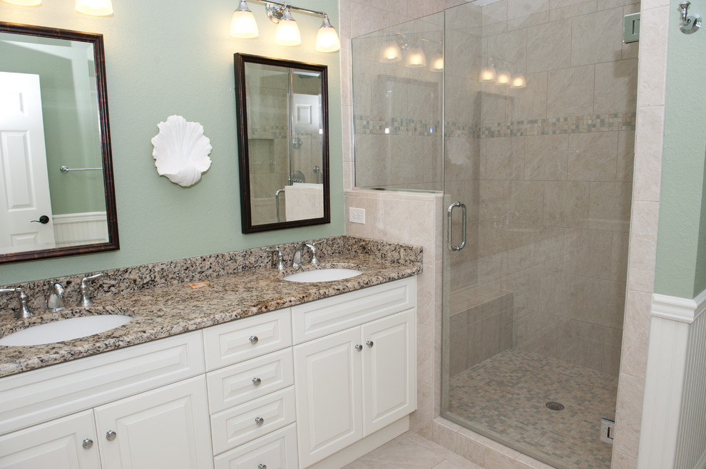 Example of a large beach style master beige tile and ceramic tile ceramic tile alcove shower design in Other with raised-panel cabinets, white cabinets, green walls, an undermount sink and granite countertops