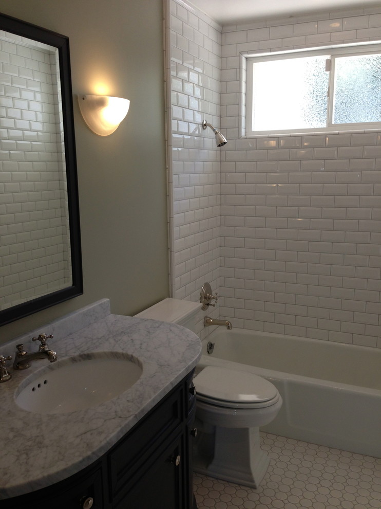 Inspiration pour une salle de bain traditionnelle avec un lavabo encastré, un combiné douche/baignoire, WC séparés, un placard à porte affleurante, des portes de placard noires, un plan de toilette en marbre, un carrelage blanc et un carrelage métro.