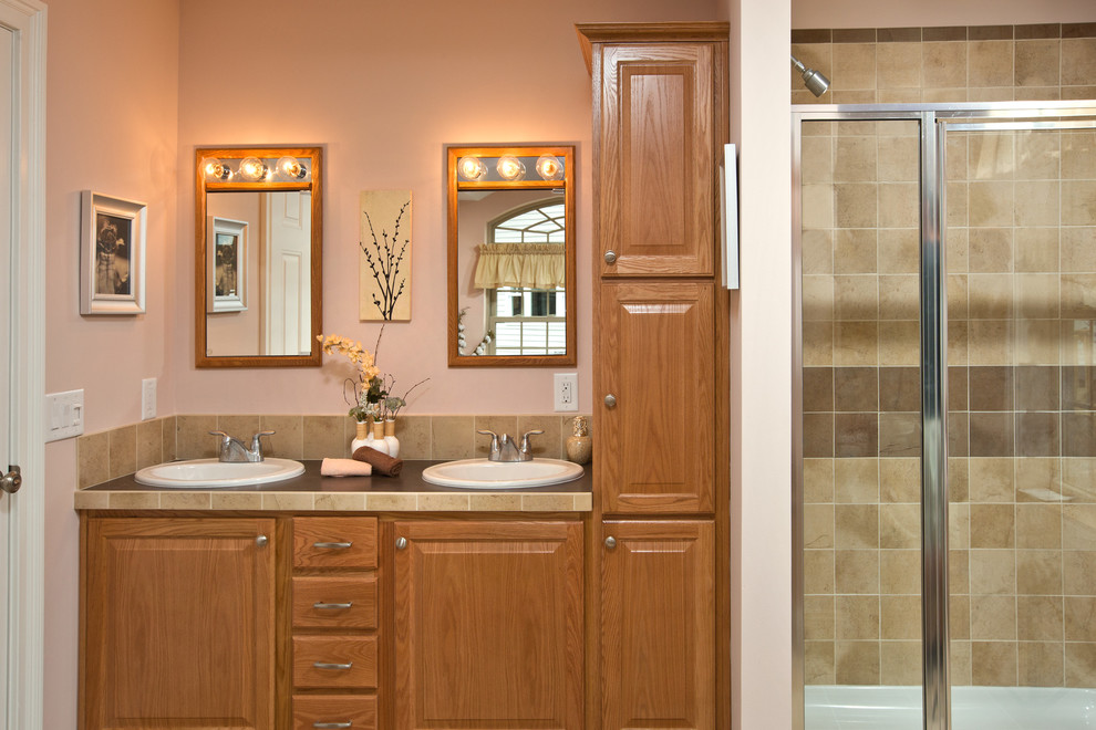 Photo of a medium sized traditional ensuite bathroom in Philadelphia with a built-in sink, flat-panel cabinets, light wood cabinets, laminate worktops, an alcove bath, beige tiles, ceramic tiles, beige walls and ceramic flooring.