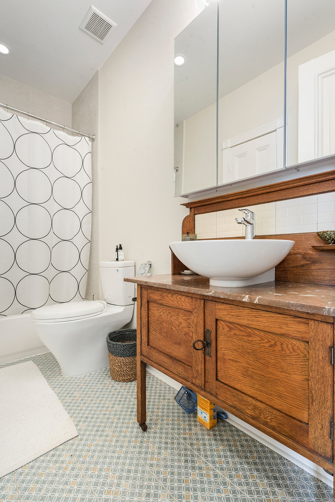 Klassisk inredning av ett brun brunt badrum, med skåp i mellenmörkt trä, ett badkar i en alkov, en dusch/badkar-kombination, beige väggar, ett fristående handfat, träbänkskiva, grått golv, dusch med duschdraperi och skåp i shakerstil