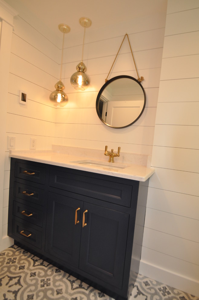 Medium sized coastal bathroom in Boston with beaded cabinets, blue cabinets, an alcove bath, a one-piece toilet, white tiles, ceramic tiles, white walls, cement flooring, a submerged sink, engineered stone worktops and grey floors.