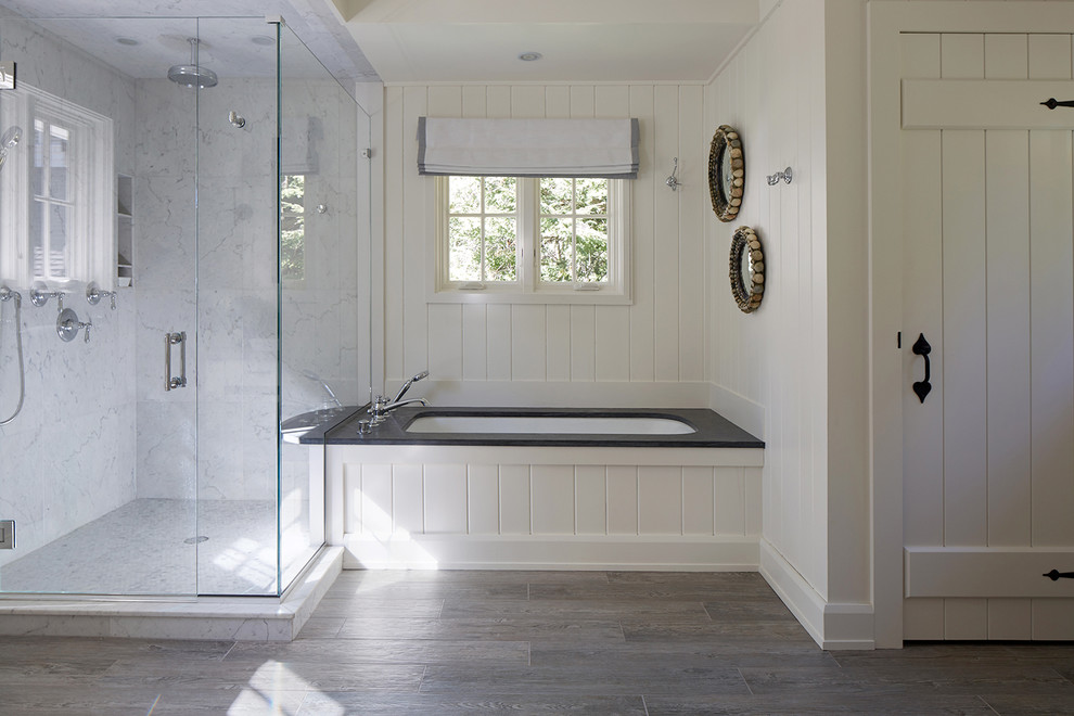 На фото: ванная комната в стиле кантри с полновстраиваемой ванной, угловым душем, белой плиткой, белыми стенами, серым полом и черной столешницей с
