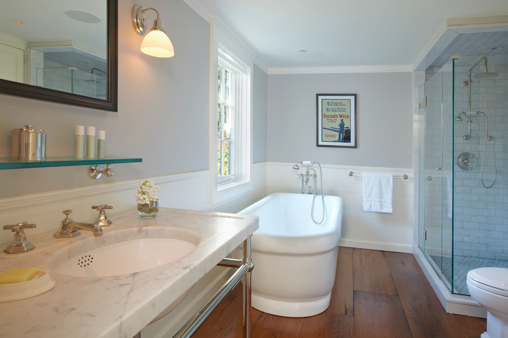 Bathroom - mid-sized transitional master white tile and subway tile medium tone wood floor bathroom idea in New York with a pedestal sink, recessed-panel cabinets, white cabinets, marble countertops, a one-piece toilet and gray walls