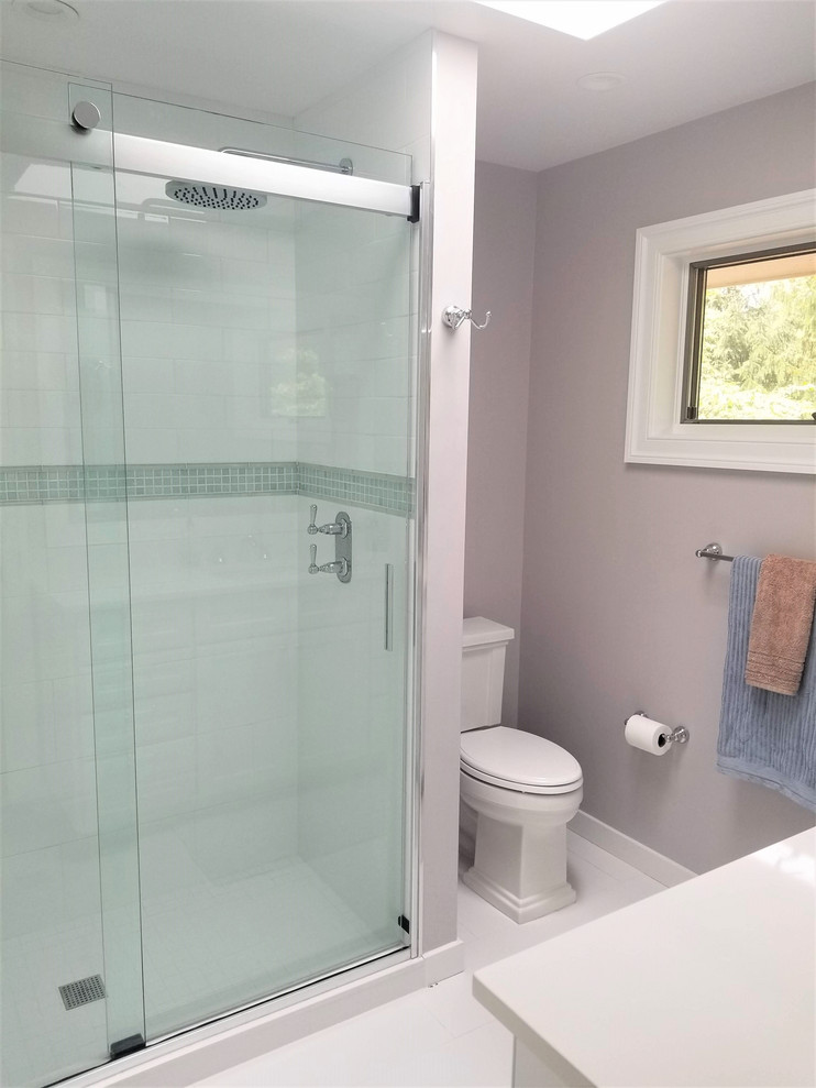 This is an example of a medium sized traditional family bathroom in New York with shaker cabinets, white cabinets, an alcove shower, a one-piece toilet, white tiles, porcelain tiles, purple walls, porcelain flooring, a submerged sink, engineered stone worktops, white floors, a sliding door and white worktops.