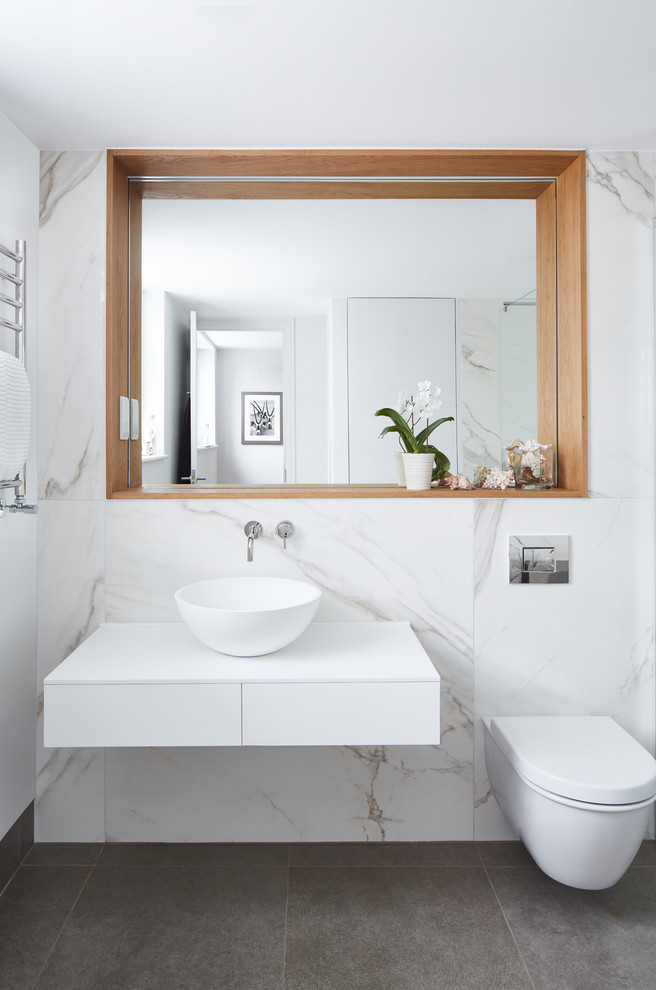 Photo of a medium sized contemporary family bathroom in London with white cabinets, a walk-in shower, a wall mounted toilet, white tiles, marble tiles, white walls, a vessel sink, grey floors, an open shower and white worktops.