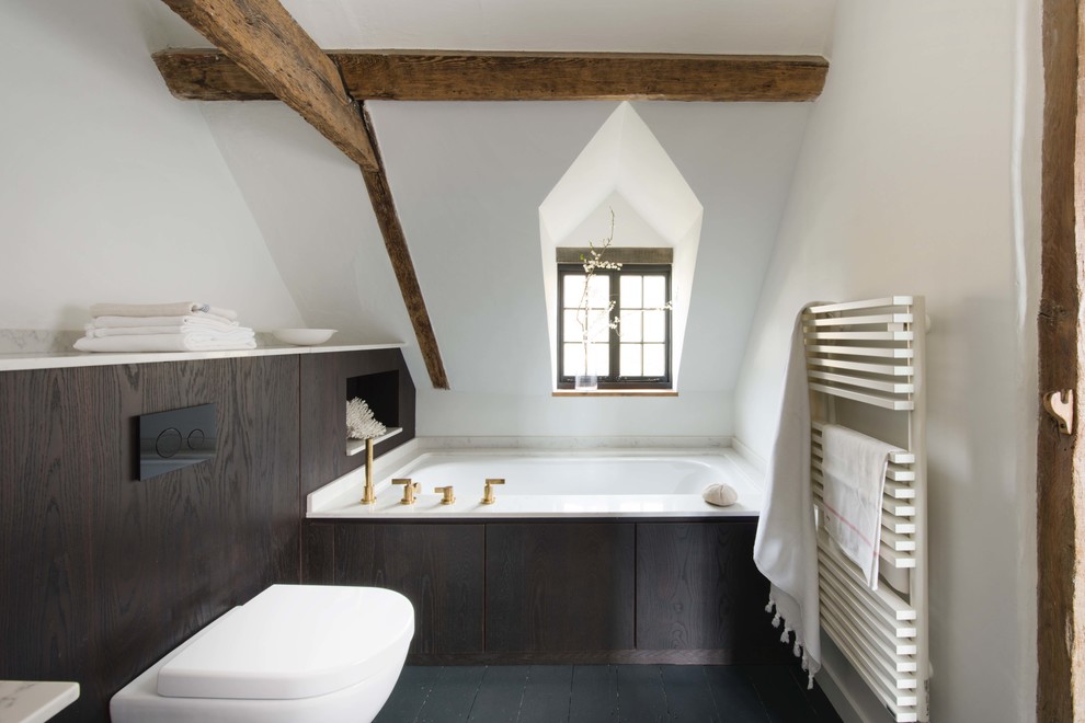 Design ideas for a small contemporary bathroom in Sussex with flat-panel cabinets, brown cabinets, a corner bath, a wall mounted toilet, white walls, black floors and white worktops.