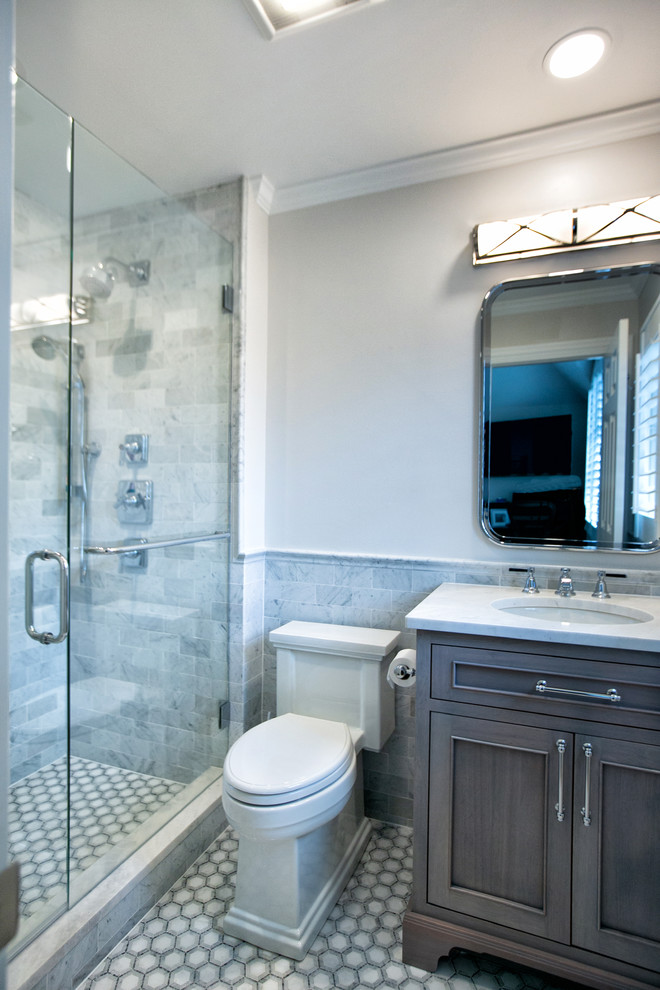 Klassisk inredning av ett mellanstort vit vitt badrum, med möbel-liknande, grå skåp, en dusch i en alkov, en toalettstol med hel cisternkåpa, vit kakel, marmorkakel, grå väggar, marmorgolv, ett undermonterad handfat, marmorbänkskiva, vitt golv och dusch med gångjärnsdörr