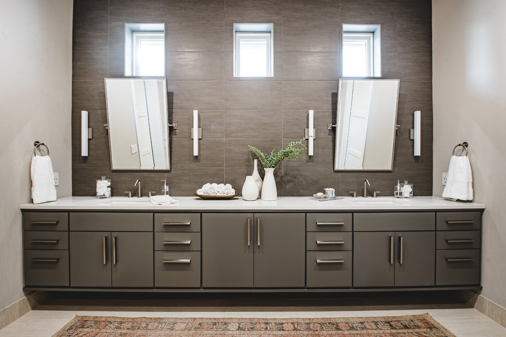 Пример оригинального дизайна: главная ванная комната среднего размера в современном стиле с плоскими фасадами, серыми фасадами, коричневой плиткой, серыми стенами, врезной раковиной, каменной плиткой, полом из травертина и белой столешницей