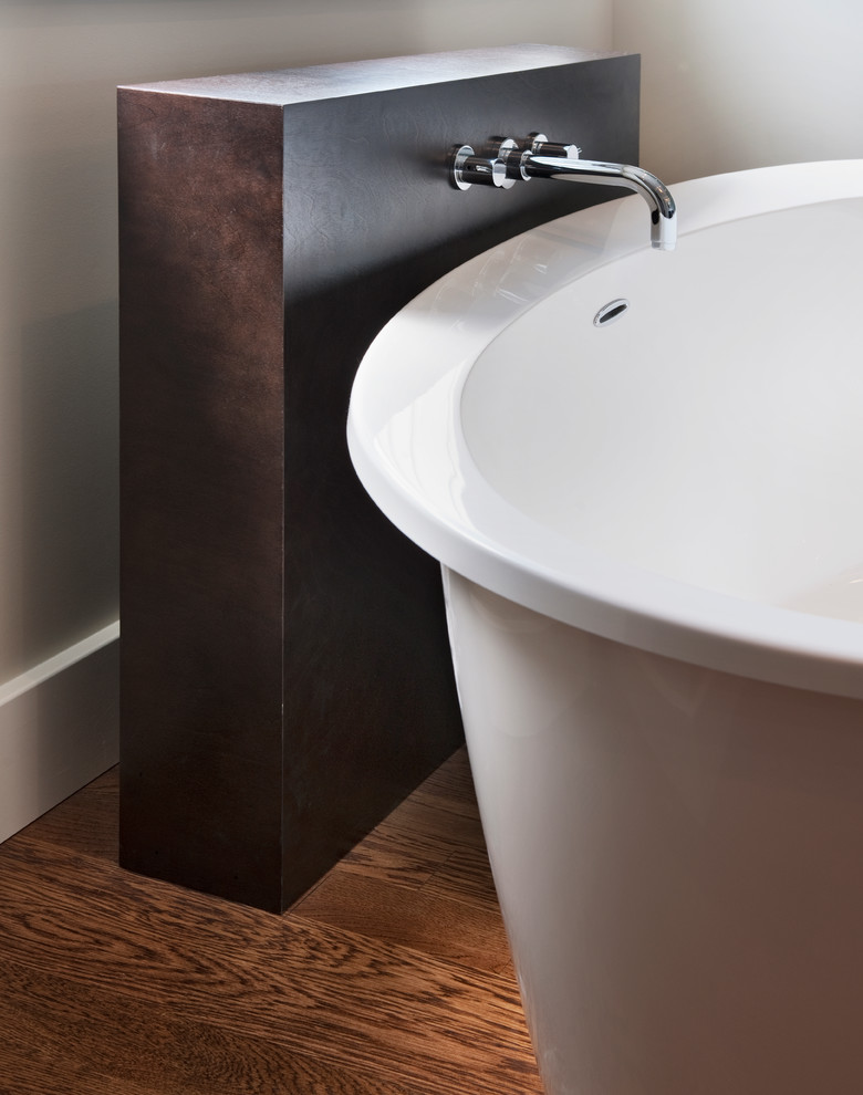 Photo of a modern ensuite bathroom in Ottawa with a vessel sink, flat-panel cabinets, dark wood cabinets, engineered stone worktops, a freestanding bath, a built-in shower, a one-piece toilet, white tiles, porcelain tiles, grey walls and medium hardwood flooring.