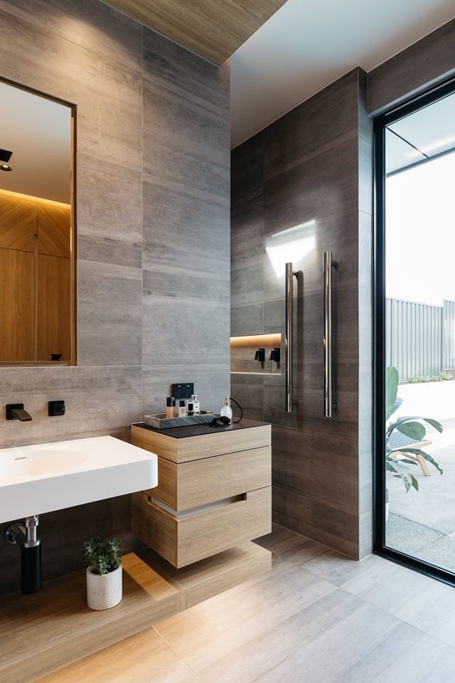 Modern inredning av ett stort grå grått badrum med dusch, med möbel-liknande, skåp i ljust trä, grå kakel, grå väggar, klinkergolv i porslin, en öppen dusch, porslinskakel, bänkskiva i kvarts, med dusch som är öppen, ett väggmonterat handfat och grått golv