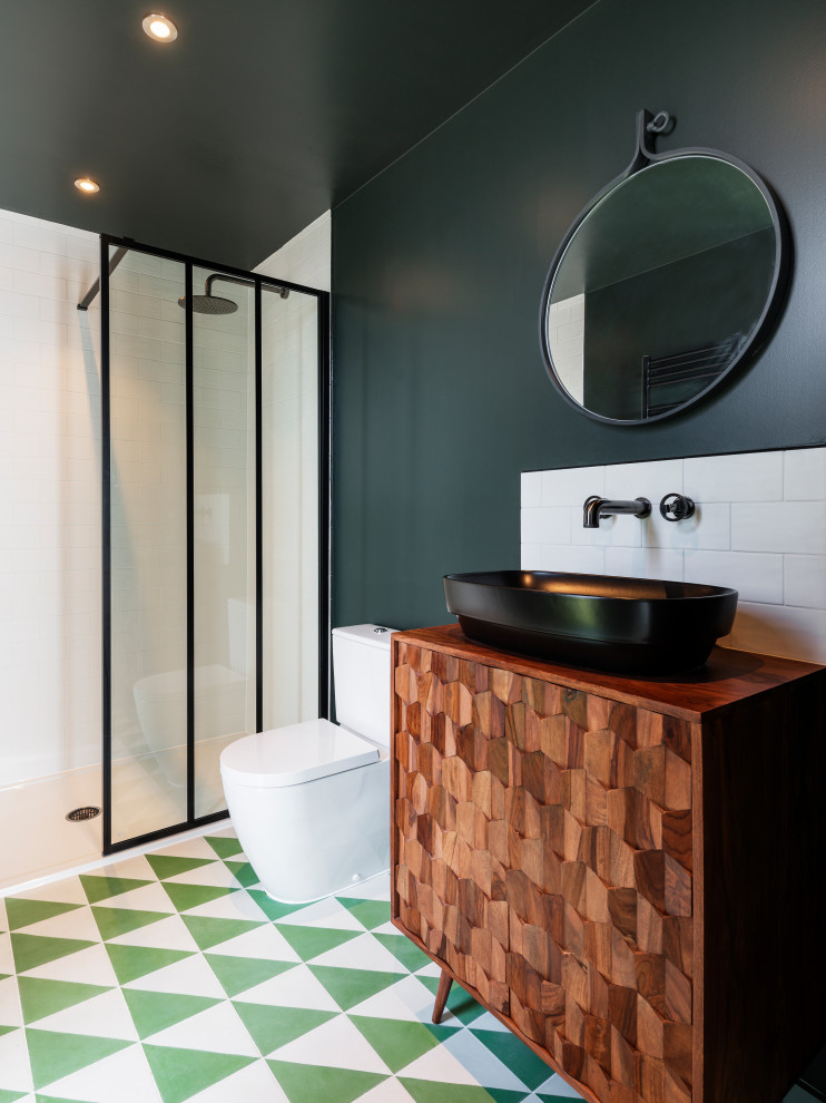 Idée de décoration pour une grande salle de bain design en bois brun avec WC séparés, un carrelage blanc, un carrelage métro, un mur vert, une vasque, un plan de toilette en bois, un sol multicolore, un plan de toilette marron et un placard à porte plane.