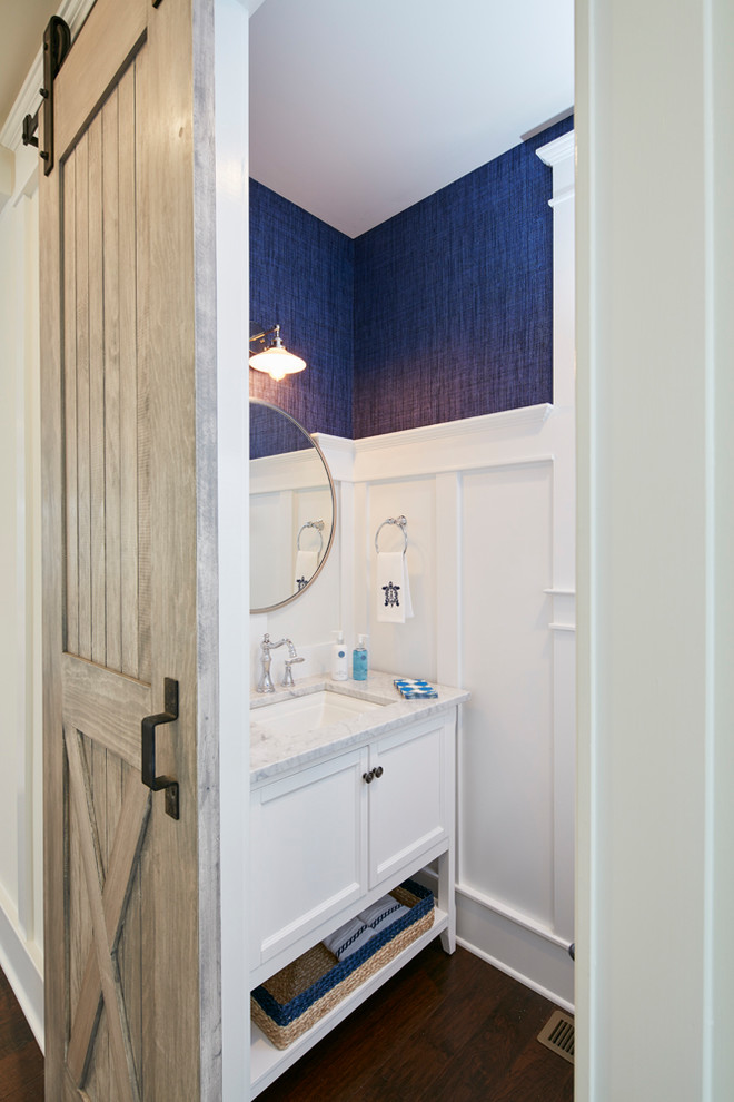Foto di una piccola stanza da bagno stile marino con ante in stile shaker, ante bianche, pareti blu, pavimento in legno massello medio, lavabo sottopiano e pavimento marrone