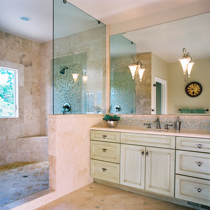 Klassisk inredning av ett mellanstort en-suite badrum, med ett undermonterad handfat, luckor med upphöjd panel, gröna skåp, granitbänkskiva, ett platsbyggt badkar, en hörndusch, en toalettstol med hel cisternkåpa, beige kakel, stenkakel, beige väggar och travertin golv