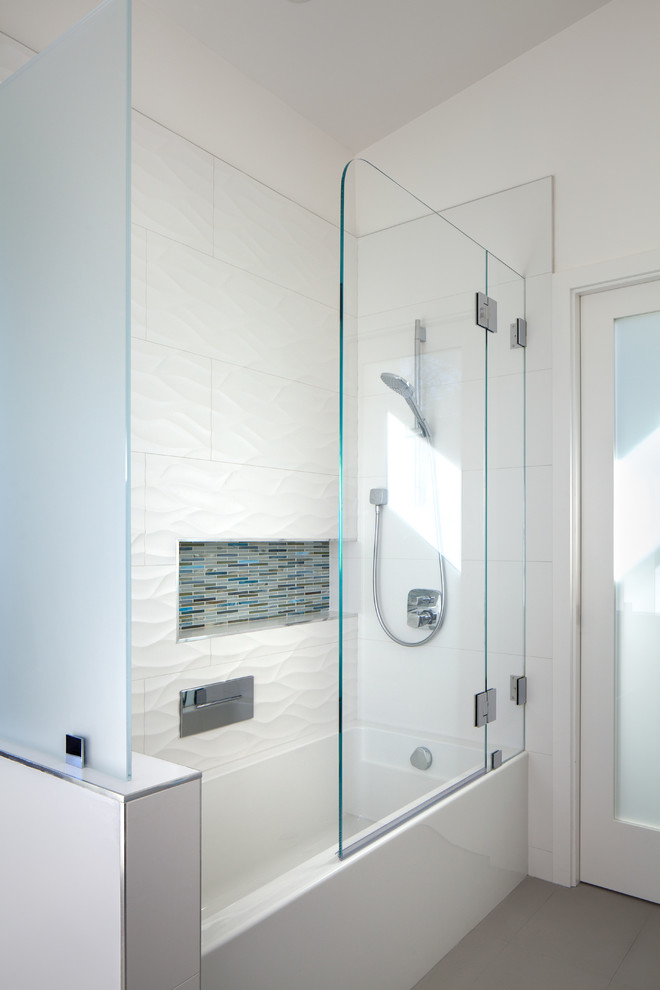 На фото: ванная комната в стиле модернизм с ванной в нише, душем над ванной, белой плиткой, керамогранитной плиткой, белыми стенами и душем с распашными дверями с