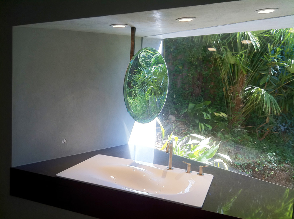 This is an example of a medium sized modern ensuite bathroom in San Francisco with a built-in sink, flat-panel cabinets, black cabinets, solid surface worktops, a japanese bath, a walk-in shower, a wall mounted toilet, beige walls and concrete flooring.