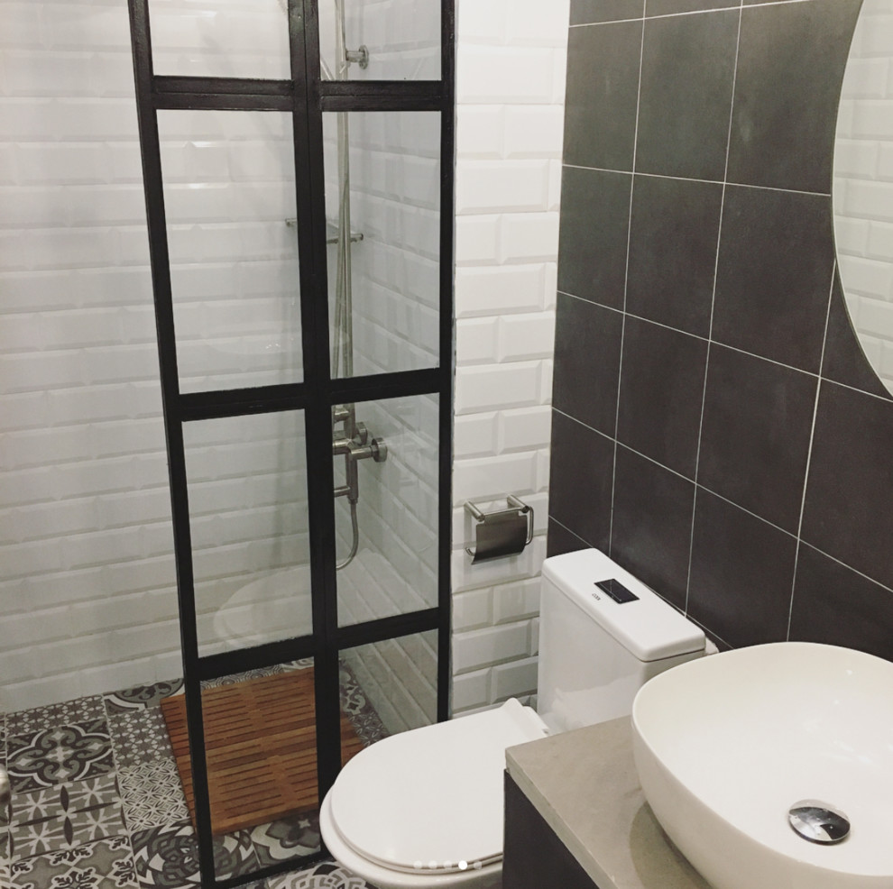 Industriell inredning av ett litet badrum med dusch, med släta luckor, svarta skåp, vit kakel, tunnelbanekakel, flerfärgade väggar, klinkergolv i keramik, bänkskiva i betong och flerfärgat golv