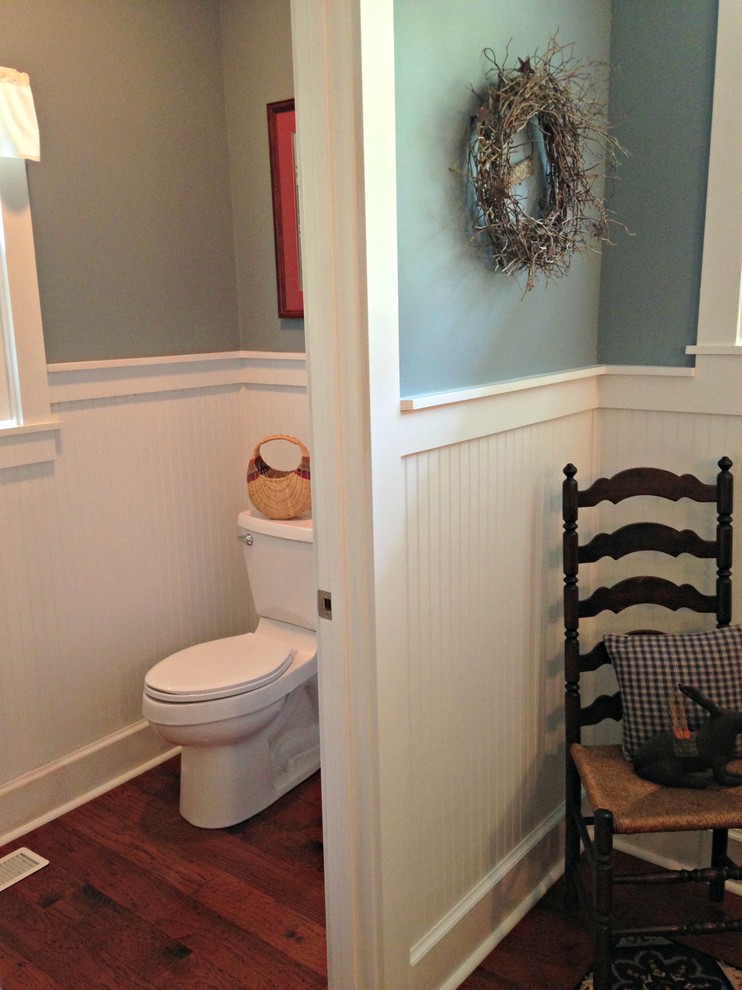 Mid-sized elegant medium tone wood floor powder room photo in Indianapolis with an undermount sink, raised-panel cabinets, black cabinets, granite countertops, a two-piece toilet and blue walls