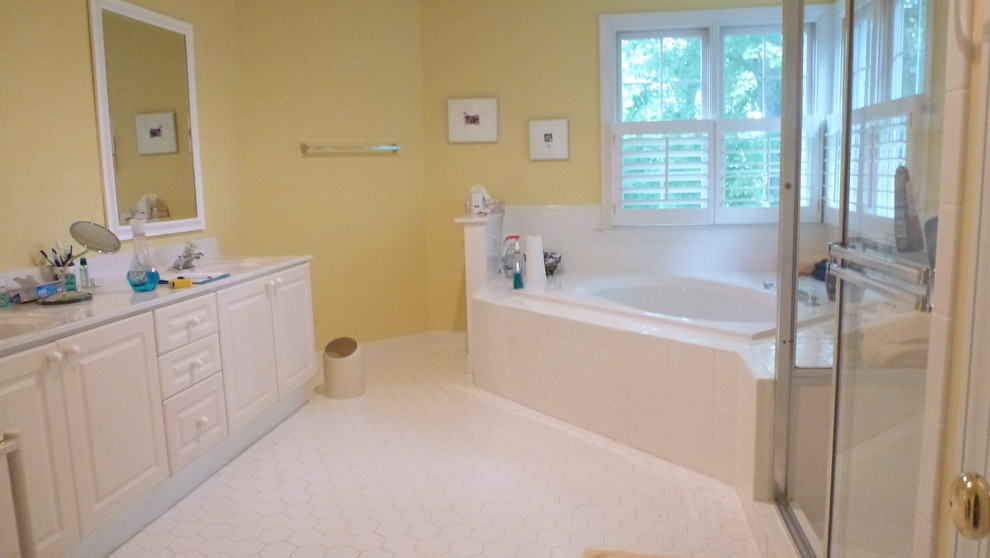 На фото: большая главная ванная комната в классическом стиле с монолитной раковиной, фасадами с выступающей филенкой, столешницей из ламината, угловой ванной, угловым душем, раздельным унитазом, белой плиткой, керамической плиткой, желтыми стенами, полом из керамической плитки и белыми фасадами