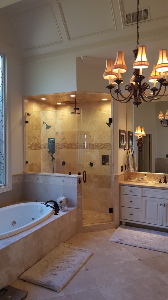 Klassisk inredning av ett stort en-suite badrum, med ett platsbyggt badkar, våtrum, beige kakel, travertinkakel, travertin golv, marmorbänkskiva, brunt golv, dusch med gångjärnsdörr, luckor med upphöjd panel, beige skåp, beige väggar och ett integrerad handfat