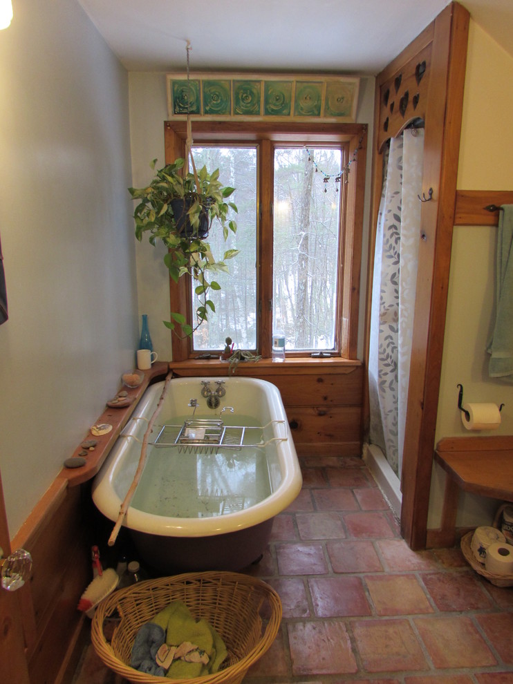 Lantlig inredning av ett litet en-suite badrum, med släta luckor, vita skåp, ett badkar med tassar, en toalettstol med separat cisternkåpa, klinkergolv i terrakotta, bänkskiva i täljsten, dusch med duschdraperi och blå väggar