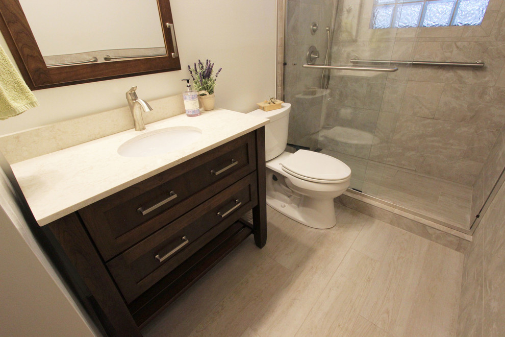 Inspiration for a small transitional master beige tile and porcelain tile vinyl floor bathroom remodel in Cleveland with recessed-panel cabinets, dark wood cabinets, a two-piece toilet, beige walls, an undermount sink, quartz countertops and beige countertops