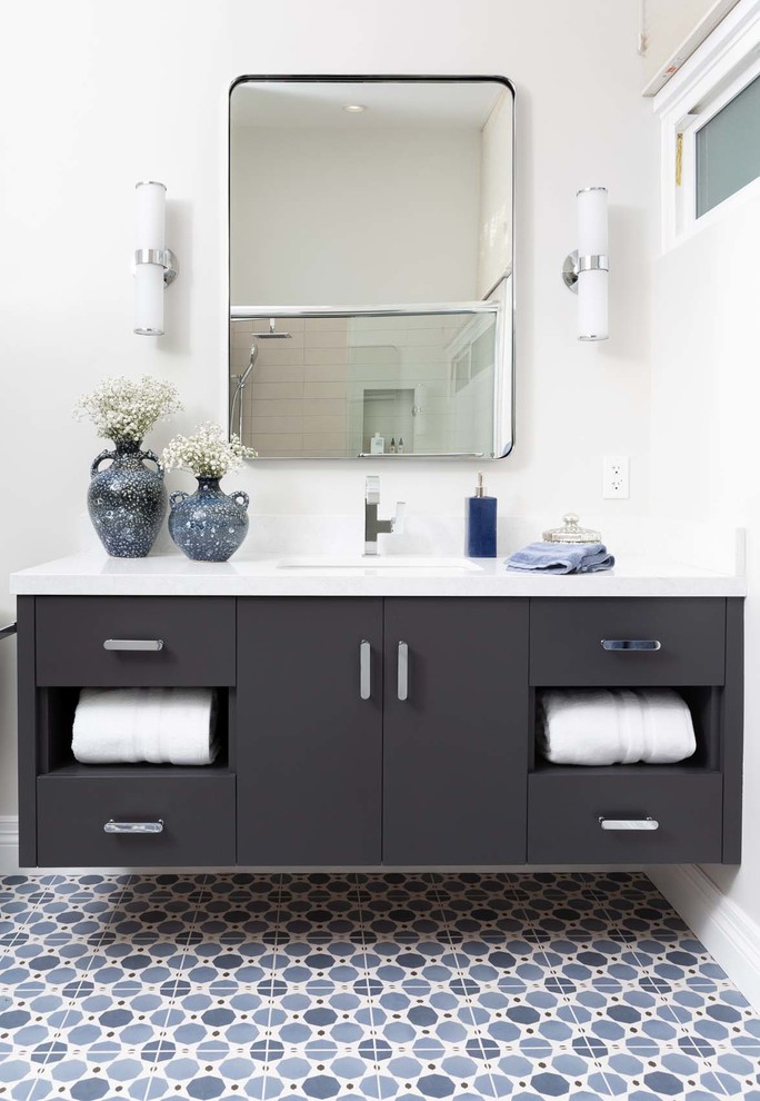 На фото: ванная комната среднего размера в современном стиле с плоскими фасадами, серыми фасадами, ванной в нише, душем над ванной, унитазом-моноблоком, серой плиткой, керамической плиткой, серыми стенами, полом из керамической плитки, врезной раковиной, столешницей из искусственного кварца, синим полом, душем с раздвижными дверями и белой столешницей