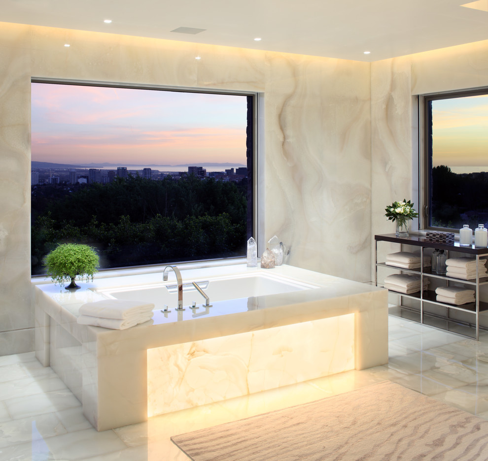 Trendy white tile and stone slab bathroom photo in Los Angeles with an undermount tub