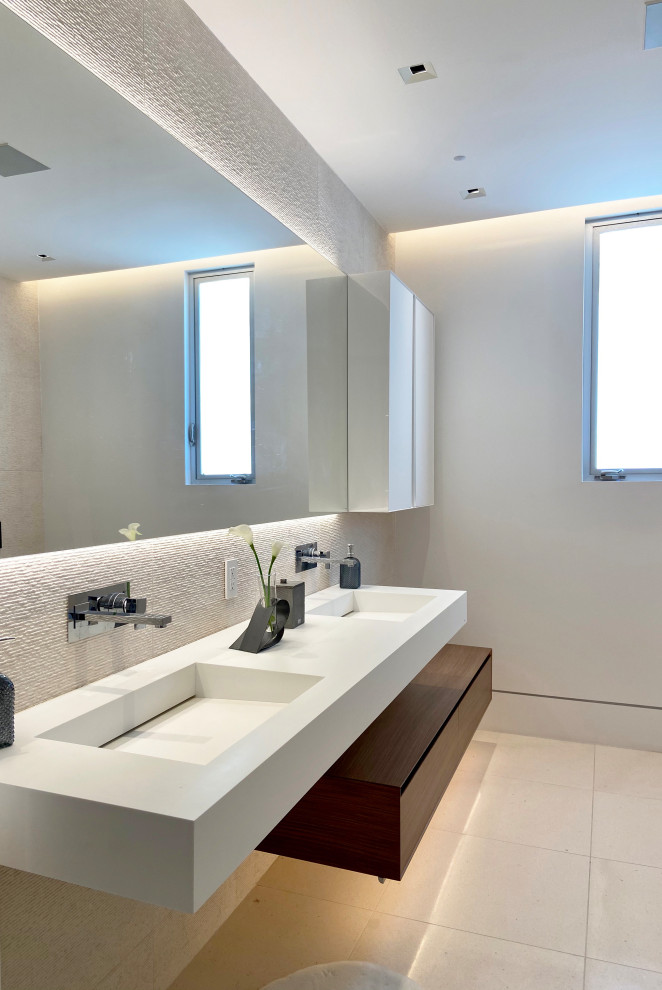 Inredning av ett modernt mellanstort vit vitt badrum med dusch, med släta luckor, bruna skåp, ett fristående badkar, en hörndusch, en vägghängd toalettstol, beige kakel, stenkakel, beige väggar, kalkstensgolv, ett integrerad handfat, bänkskiva i akrylsten och dusch med gångjärnsdörr