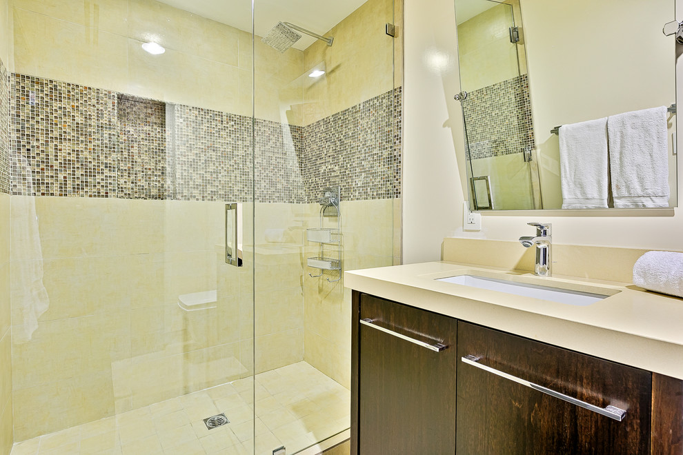 Inspiration pour une salle de bain design en bois foncé avec un placard à porte plane, un carrelage gris, mosaïque, un mur beige, un lavabo encastré et une cabine de douche à porte battante.
