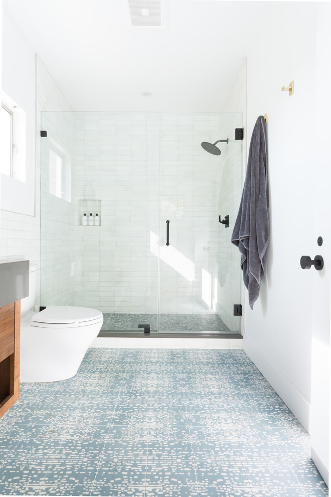Пример оригинального дизайна: ванная комната среднего размера в стиле ретро с плоскими фасадами, темными деревянными фасадами, душем в нише, унитазом-моноблоком, белой плиткой, керамической плиткой, белыми стенами, полом из цементной плитки, врезной раковиной, столешницей из искусственного кварца, синим полом, душем с распашными дверями и белой столешницей