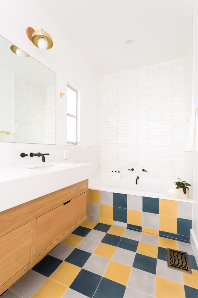 Photo of a contemporary bathroom in Los Angeles with flat-panel cabinets, medium wood cabinets, an alcove bath, white tiles, a submerged sink, multi-coloured floors, white worktops, double sinks and a floating vanity unit.