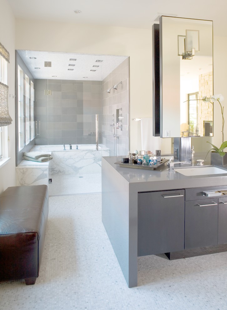 Cette image montre une salle de bain design avec un lavabo encastré, un placard à porte plane, des portes de placard grises, une douche double et un carrelage gris.