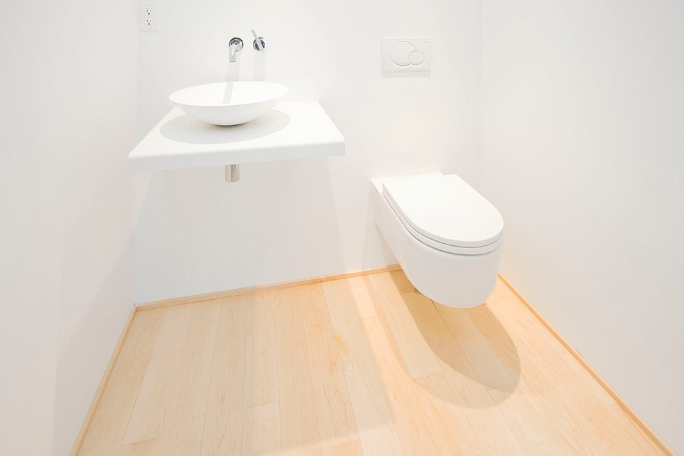 バンクーバーにあるモダンスタイルのおしゃれなトイレ・洗面所 (ベッセル式洗面器、壁掛け式トイレ、白い壁、淡色無垢フローリング) の写真