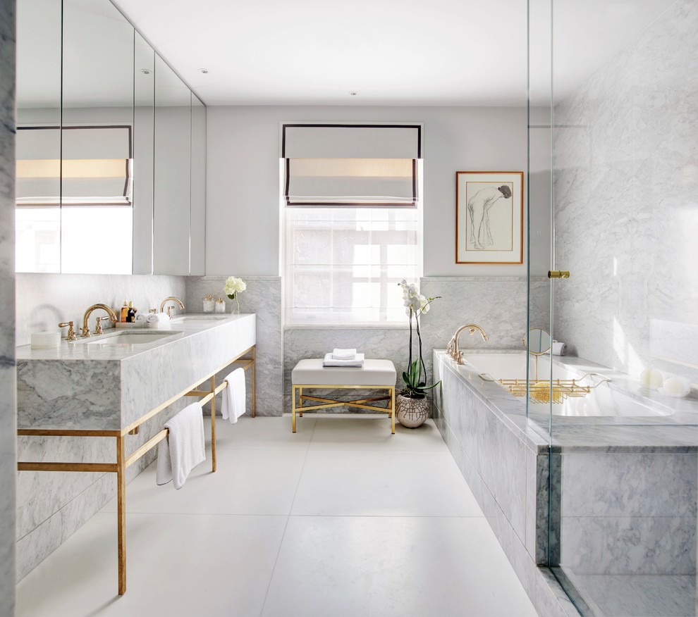 Idée de décoration pour une salle de bain principale design avec un placard à porte plane, des portes de placard grises, une baignoire encastrée, un carrelage gris, un mur blanc, un plan vasque, un sol blanc et un plan de toilette gris.