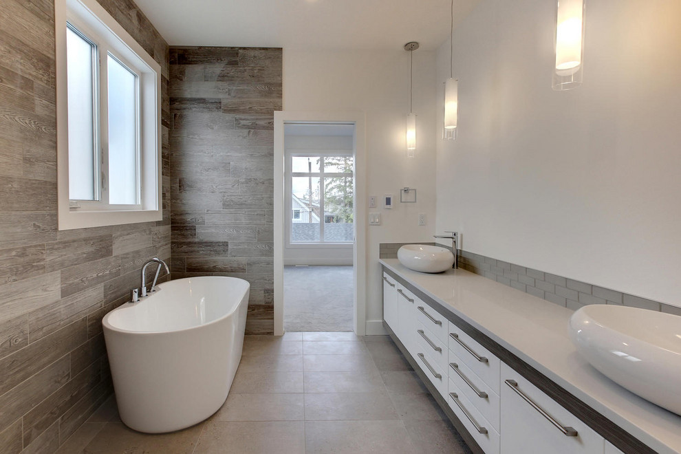 Medium sized contemporary ensuite bathroom in Edmonton with flat-panel cabinets, white cabinets, a freestanding bath, a walk-in shower, a one-piece toilet, grey tiles, glass tiles, white walls, porcelain flooring, a vessel sink, quartz worktops, beige floors, an open shower and white worktops.